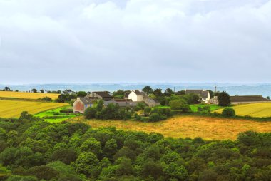 Scenic view on agricultural landscape with a farm house in rural Brittany, France clipart