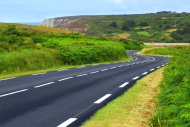 Winding road along the ocean coast in Brittany, France clipart