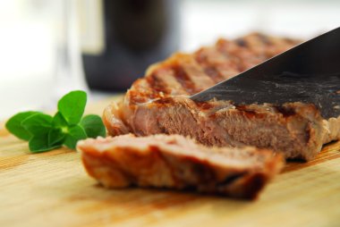 Grilled steak being cut on a cutting board clipart