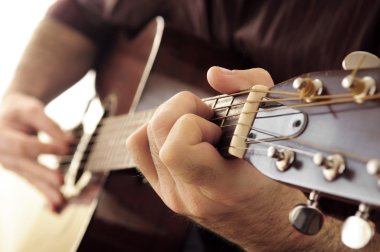 Hands of a person playing an acoustic guitar close up clipart