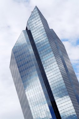 Corporate building with glass walls reflecting clouds clipart