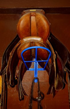 Two saddles on a rack in a tack room, horseback riding equipment clipart