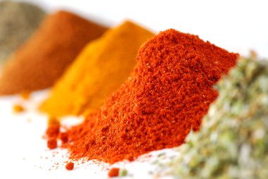 Heaps of various ground spices on white background clipart