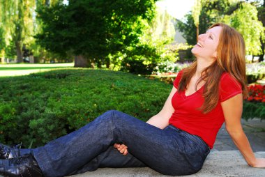 Happy mature woman relaxing in summer park clipart