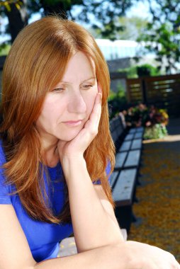 Üzgün ve depresyonda yalnız bir bankta oturan arayan Olgun kadın