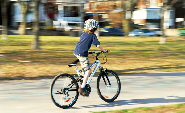 Panning shot of a boy riding a bicycle, motion blurred background