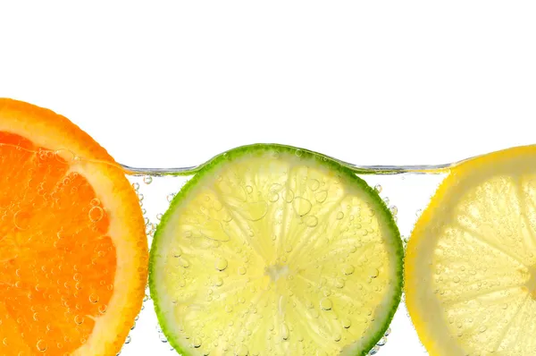 Limão de laranja e fatias de limão na água — Fotografia de Stock