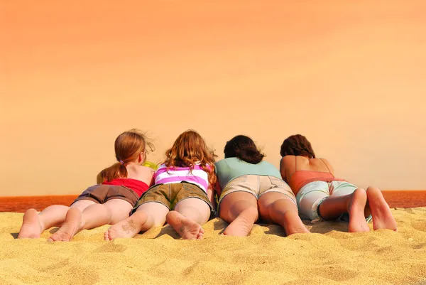 Четыре Девушки Лежат Пляже Оранжевым Морем Небом — стоковое фото