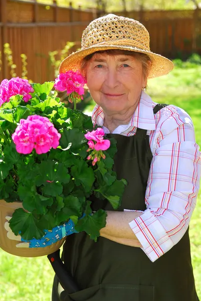 高级女子持一壶她花园 Dof 侧重于鲜花鲜花 — Stock fotografie
