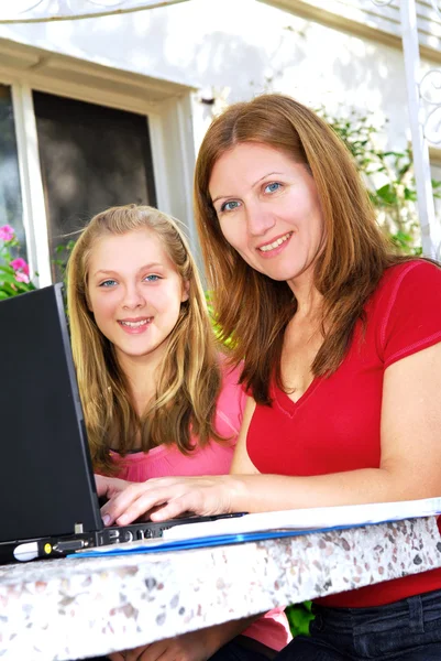 母亲和女儿在花园里在家的便携式计算机上工作 — 图库照片