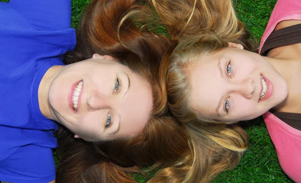 微笑的母亲和她十几岁的女儿躺在夏天公园草地上的家庭的肖像 — 图库照片