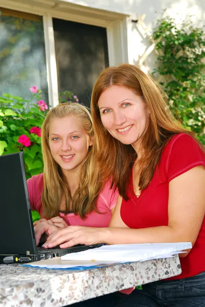 裏庭の自宅のコンピューターで働く母と娘 — ストック写真
