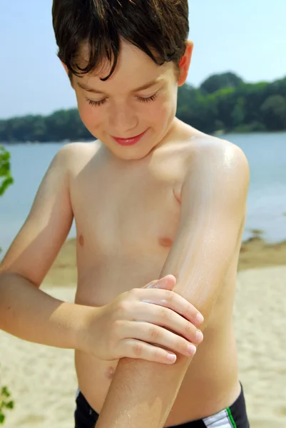 Мальчик наносит солнцезащитный крем — стоковое фото