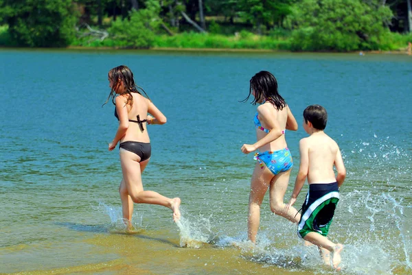 浜の水の中に実行している若い子供たちのグループ — ストック写真
