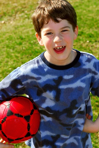 Χαριτωμένο Ευτυχείς Αγόρι Κρατώντας Ένα Κόκκινο Ποδόσφαιρο Αγόρι Εκτός — Φωτογραφία Αρχείου