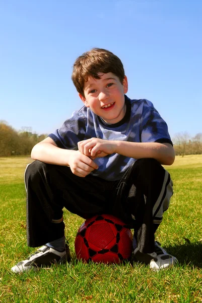 Χαριτωμένο Ευτυχείς Αγόρι Κάθεται Μια Μπάλα Κόκκινο Ποδοσφαίρου Έξω Από — Φωτογραφία Αρχείου