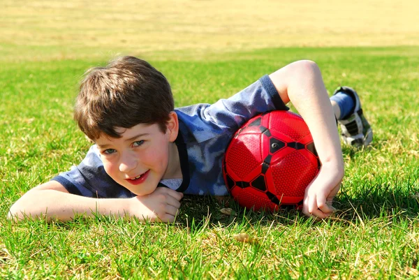 Молодой Милый Счастливый Мальчик Лежит Траве Красным Футбольным Мячом — стоковое фото