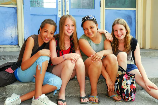 一批年轻微笑学校女生坐在学校大楼附近的步骤上的肖像 — 图库照片#