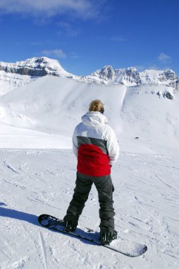 Girl on snowboard enjoying scenic view in Canadian Rocky mountains ski resort clipart