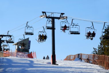 Chairlift with skiers on downhill ski resort clipart