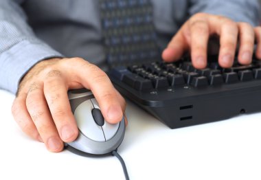 Closeup of man's hands with computer mouse and keyboard clipart