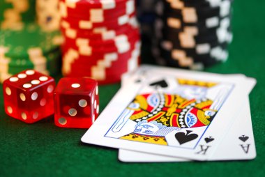 Stacks of gambling chips, playing cards and dice on green background clipart