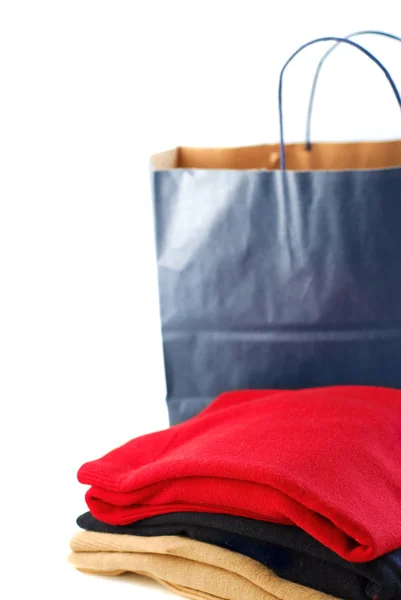 白い背景の上に紙の買い物袋で折られたセーター — ストック写真