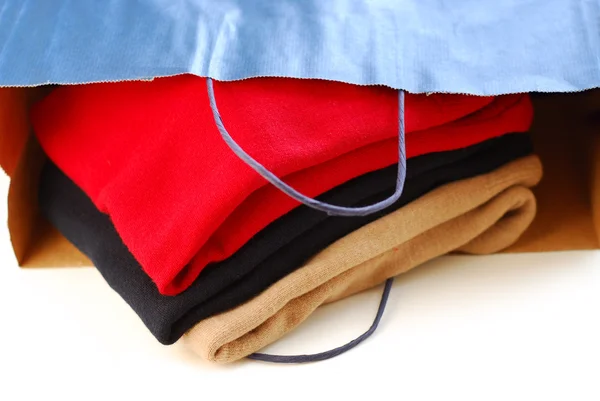 白い背景の上に紙の買い物袋で折られたセーター — ストック写真