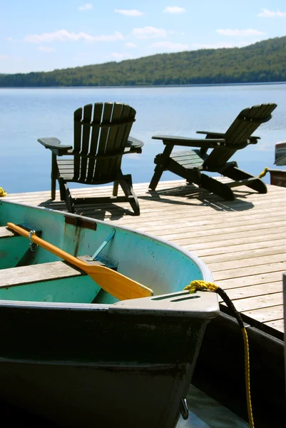 Paddle Boat Two Adirondack Wooden Chairs Dock Facing Blue Lake — Stock Photo, Image
