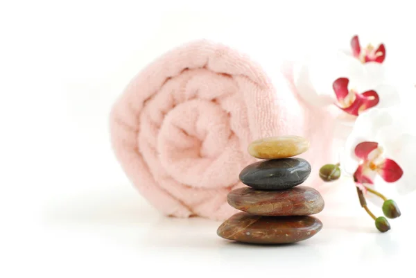 在白色背景上卷起一堆的按摩石和兰花毛巾粉色 — 图库照片
