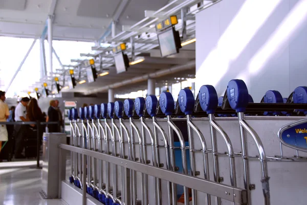 stock image Luggage carts at modern international airport, passengers at check-in counter in the background