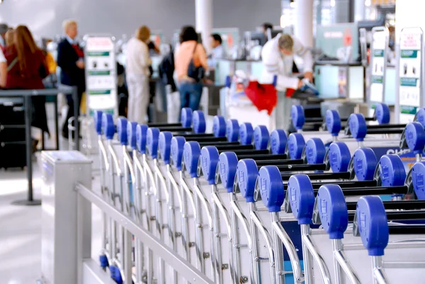 在背景中检查柜台的现代化国际机场旅客行李手推车 — 图库照片
