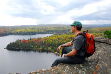 A hiker sitting on a cliff edge enjoying scenic view clipart