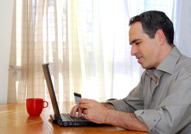 Man sitting at a desk with credit card shopping online clipart