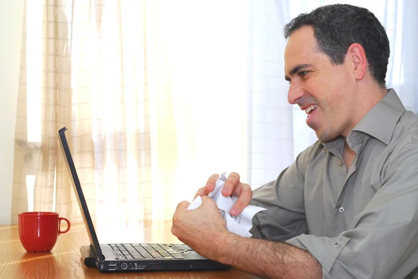 男子坐在他桌前用一台笔记本电脑 起皱论文 — 图库照片