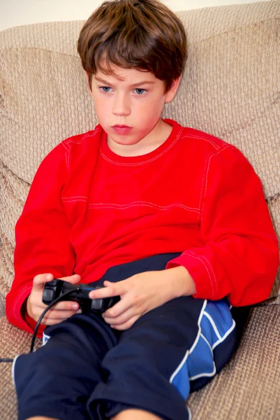 小男孩在玩视频游戏坐在沙发上 — 图库照片