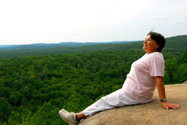 景色を楽しんで崖の端に座っている熟女 — ストック写真