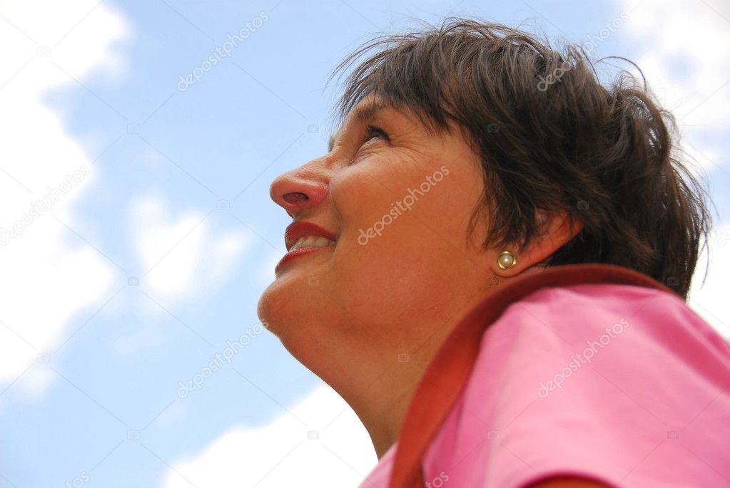 Optimistic woman looking up blue sky