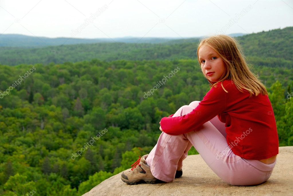 Young girl sitting on an edge of a cliff