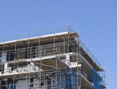 Construction with scaffolding against blue sky clipart