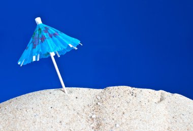 Cocktail umbrella in the sand clipart