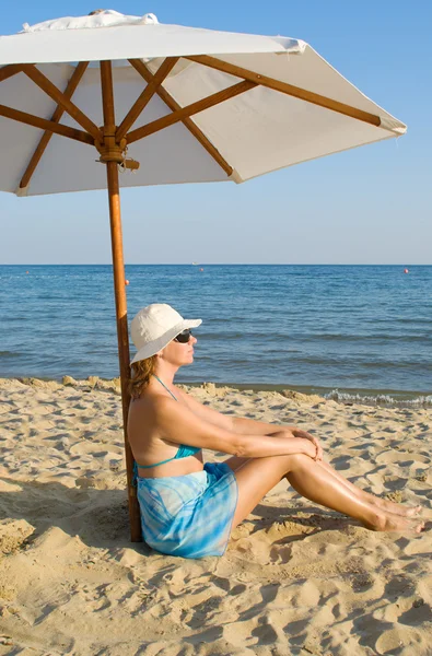 stock image The woman under a solar umbrella on a beach