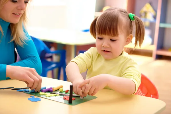 Учитель и маленькая девочка играют с пластилином — стоковое фото