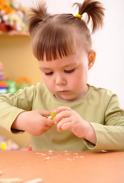 Маленька дівчинка гострить олівець — стокове фото