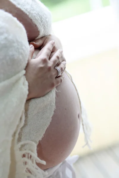 Woman holding her bare pregnant belly in — Stock Photo, Image