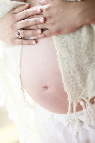 Vrouw met haar blote zwangere buik in — Stockfoto