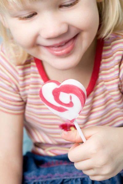 Little girl with a heart shape lollipop — Stock Photo, Image