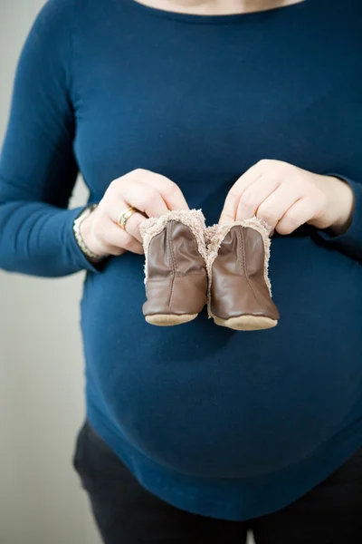 Schwangere Mutter mit Babystiefeln — Stockfoto