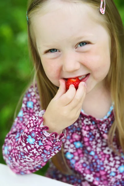 Souriante petite fille mangeant une fraise . — Photo