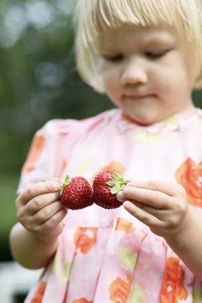 Girl holding two strawberries. — Stock Photo, Image
